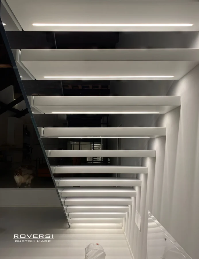 Gradini bianchi illuminati da led, scala a sbalzo dal muro con vista da sotto della scala di lusso